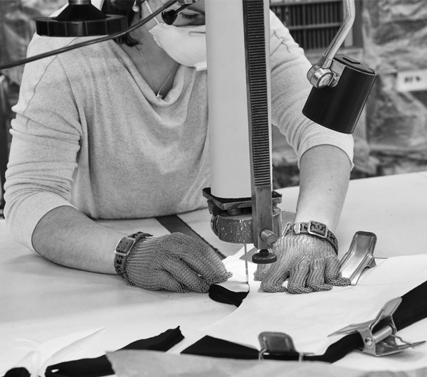 Découpe de tissus à la scie à ruban. Afin de limiter les déchets, nous optimisons la découpe grâce à des logiciels de placement. Même si nous limitons les chutes de tissus, elles sont inévitables, elle sont donc recyclées par une société locale.